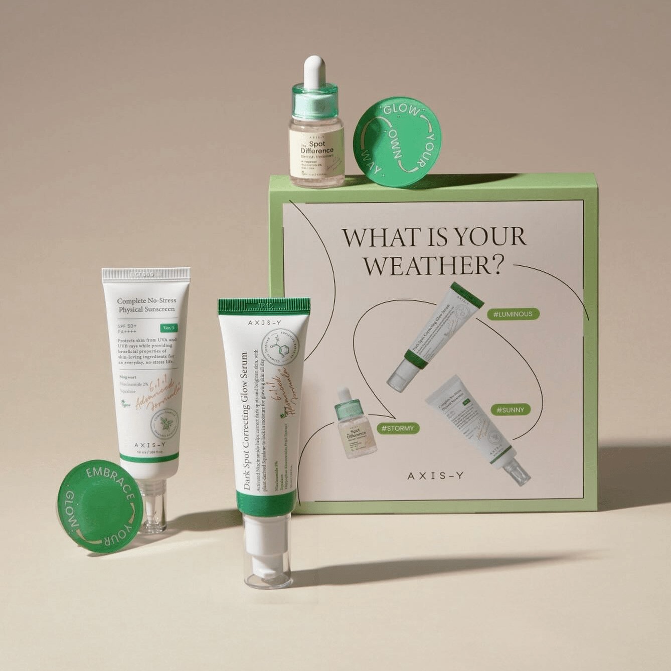 Axis-Y 'What is your weather?' product set — sunscreen, serum, and box on a warm neutral backdrop