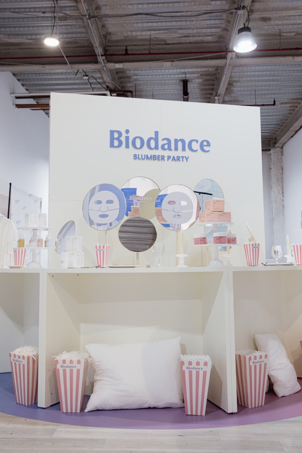 Biodance Slumber Party backdrop with mirrors, testers and striped popcorn boxes
